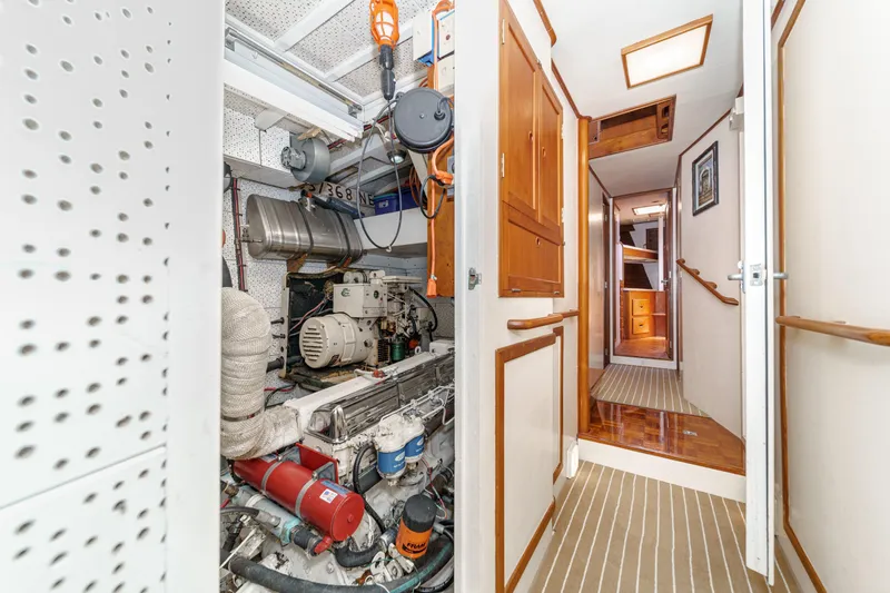 Slide: The Image of Engine room and hallway of a 1971 Grand Banks boat, featuring wooden cabinetry and striped flooring. - 51