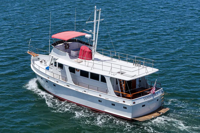 Slide: The Image of 1971 Grand Banks yacht cruising on open water with red canopy and American flag. - 56