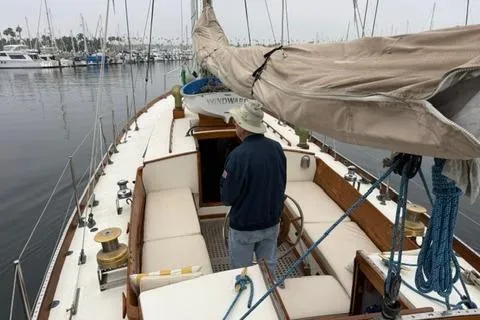 Slide: The Image of 1962 Lapworth Sloop sailboat with a person on deck, docked in a marina. - 12
