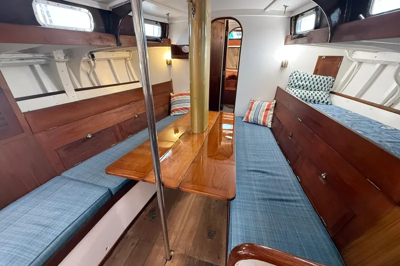 Slide: The Image of Interior of a 1962 Lapworth Sloop with wooden furnishings and blue cushions. - 16