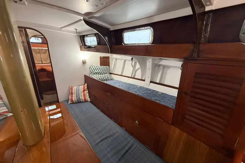 Slide: The Image of Interior of a 1962 Lapworth Sloop, featuring wooden cabinetry and cozy seating. - 18
