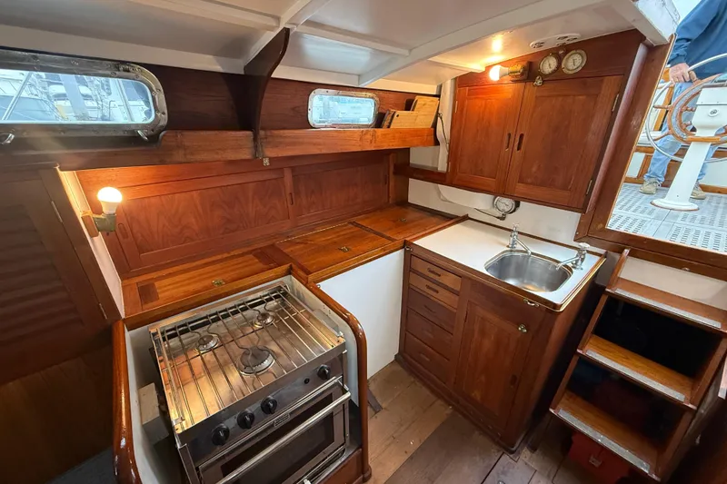 Slide: The Image of Interior of a 1962 Lapworth Sloop featuring a wooden galley with stove and sink. - 25