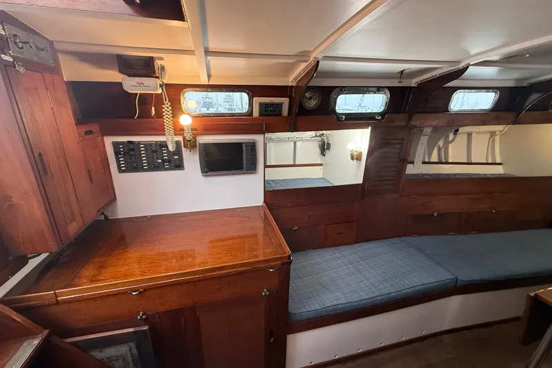 Slide: The Image of 1962 Lapworth Sloop interior with wooden cabinetry, navigation equipment, and blue cushioned seating. - 26
