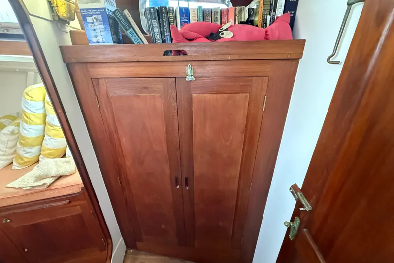 Slide: The Image of Interior of a 1962 Lapworth Sloop featuring a wooden cabinet with books and cushions. - 31