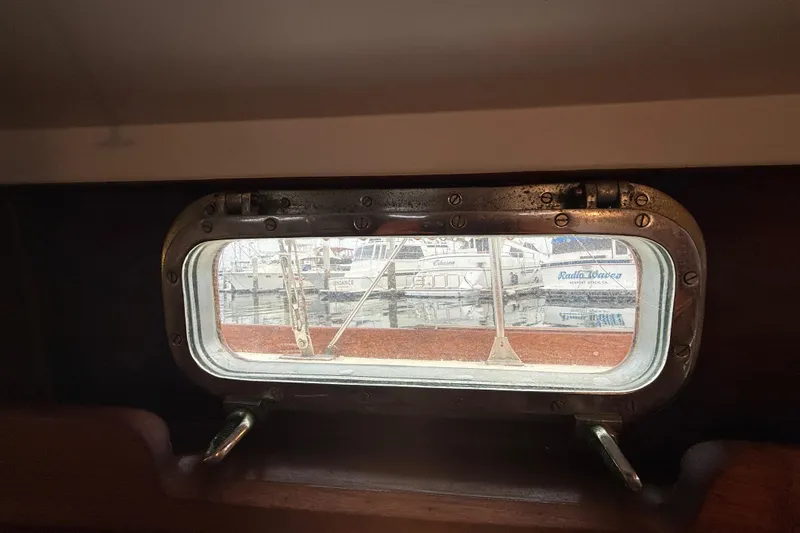Slide: The Image of Porthole view from a 1962 Lapworth Sloop, showcasing docked boats outside. - 35