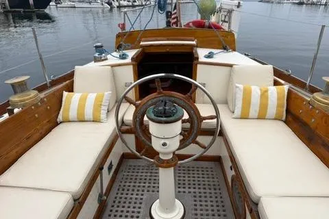 Slide: The Image of 1962 Lapworth Sloop with wooden helm and cushioned seating in a marina setting. - 9