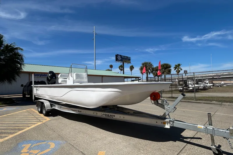 Slide: The Image of 2026 Coastal Skiff 271 boat on trailer under clear blue sky. - 4