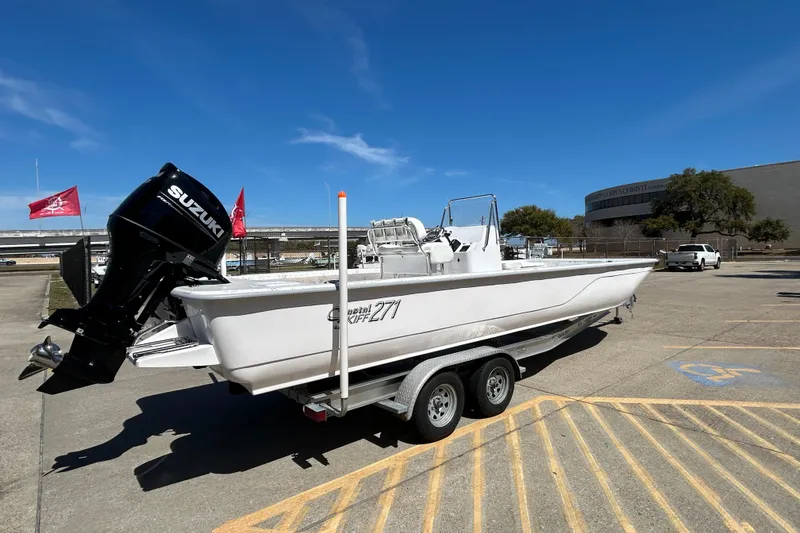 Slide: The Image of 2026 Coastal Skiff 271 boat on trailer with Suzuki outboard motor, parked outdoors. - 6