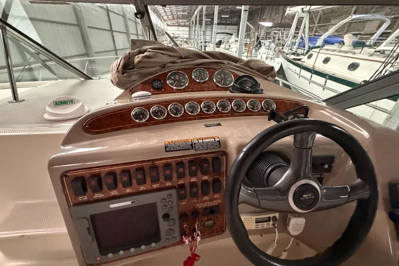 Slide: The Image of 2001 Maxum 3300 SCR boat dashboard with gauges and steering wheel in marina setting. - 27