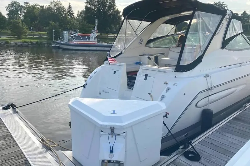 Slide: The Image of 2001 Maxum 3300 SCR boat docked at a marina with scenic background. - 3