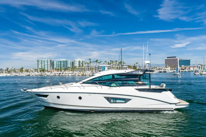 The Image of 2019 Beneteau Gran Turismo 46 yacht cruising in a marina under a clear blue sky. - 0