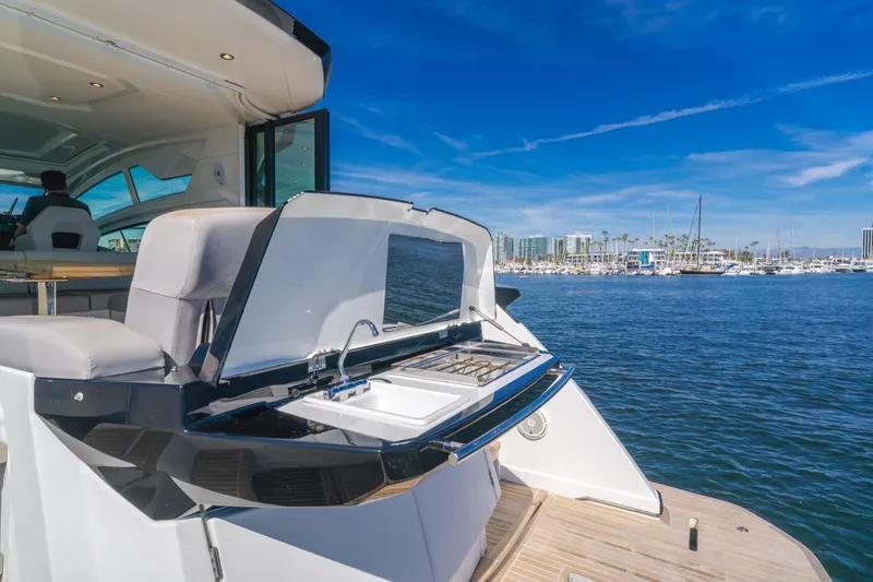 Slide: The Image of 2019 Beneteau Gran Turismo 46 yacht with outdoor kitchen, docked in a marina under clear skies. - 16