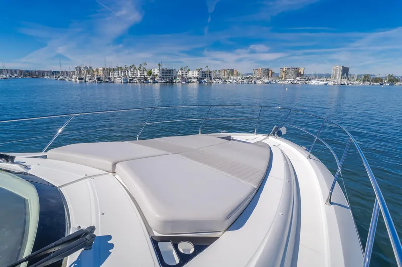 Slide: The Image of 2019 Beneteau Gran Turismo 46 yacht with sunpad, overlooking marina and cityscape. - 26