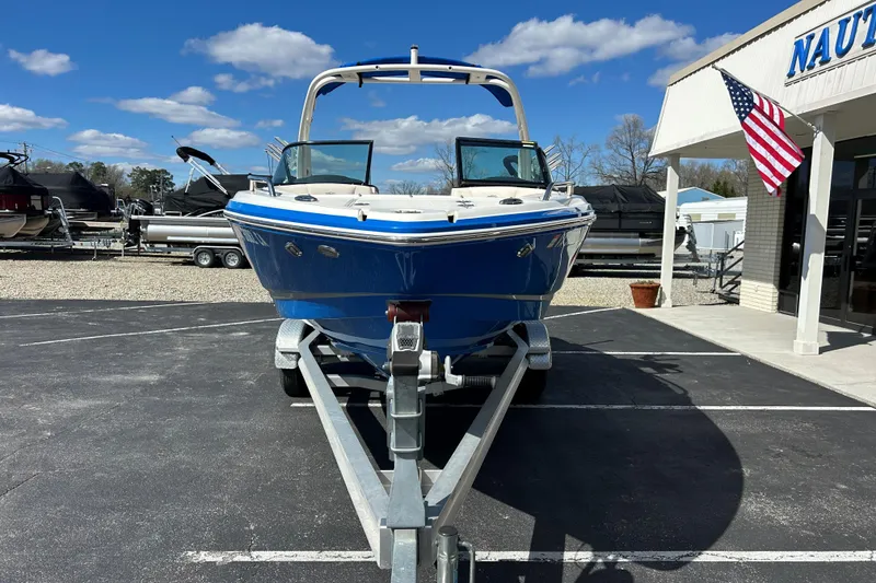 Slide: The Image of 2017 Chaparral 227 SSX Surf boat on trailer, parked outside dealership under blue sky. - 2