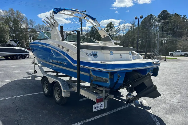 Slide: The Image of 2017 Chaparral 227 SSX Surf boat on trailer in parking lot, blue and white design. - 4