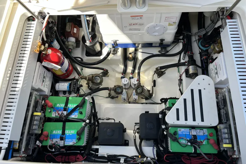 Slide: The Image of Engine compartment of a 2022 Boston Whaler 380 Realm, featuring batteries and fire extinguisher. - 21