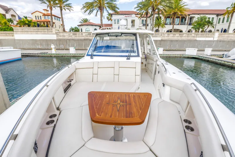 Slide: The Image of 2022 Boston Whaler 380 Realm boat docked, featuring luxurious seating and wooden table. - 25