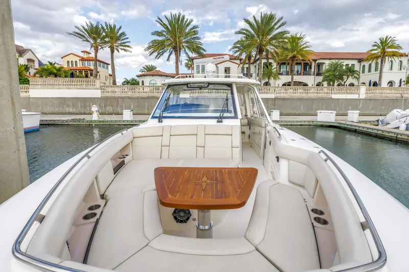 Slide: The Image of 2022 Boston Whaler 380 Realm boat docked, featuring spacious seating and elegant wooden table. - 26