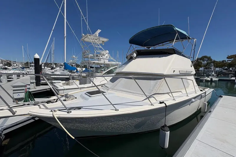 The Image of 1983 Hatteras Yachts 32 docked at marina under clear blue sky. - 0