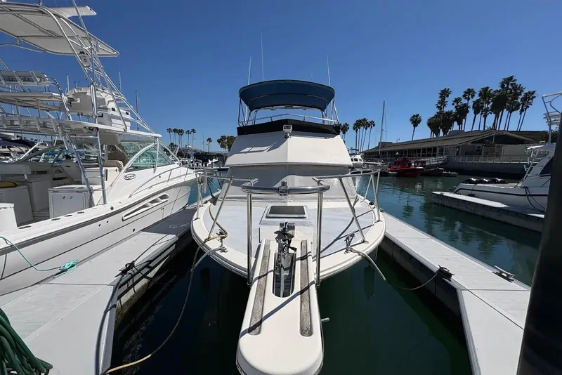 Slide: The Image of 1983 Hatteras Yachts 32 docked at marina, surrounded by other boats, under clear blue sky. - 1