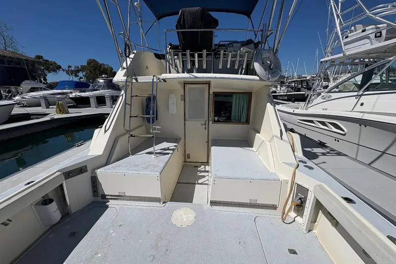 Slide: The Image of 1983 Hatteras Yachts 32 model at marina, showcasing spacious deck and seating area. - 10