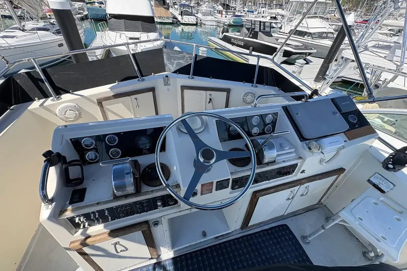 Slide: The Image of Helm of 1983 Hatteras Yachts 32, featuring steering wheel and control panels in marina setting. - 4