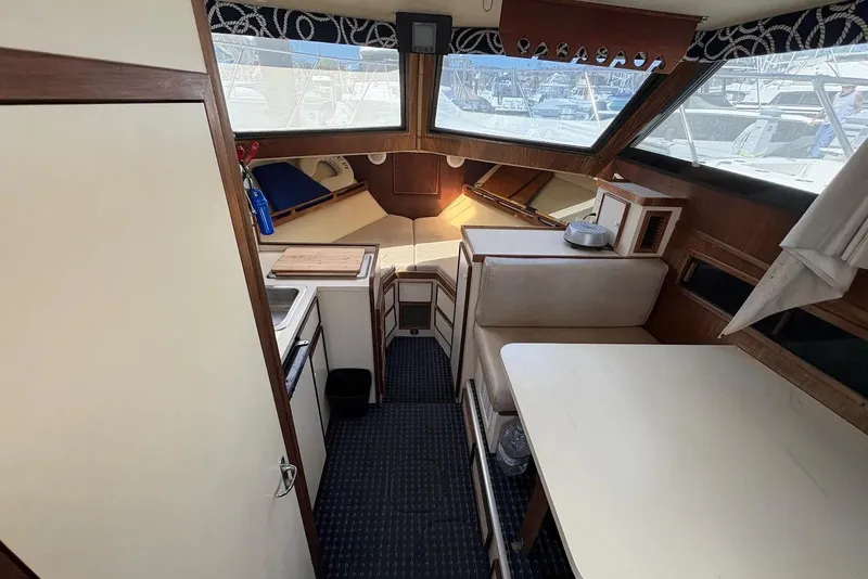 Slide: The Image of Interior of 1983 Hatteras Yachts 32, featuring cozy seating and compact kitchen area. - 5