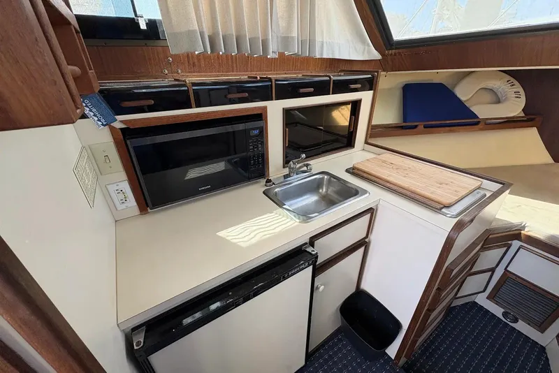 Slide: The Image of Compact kitchen area in a 1983 Hatteras Yachts 32, featuring a microwave and sink. - 8