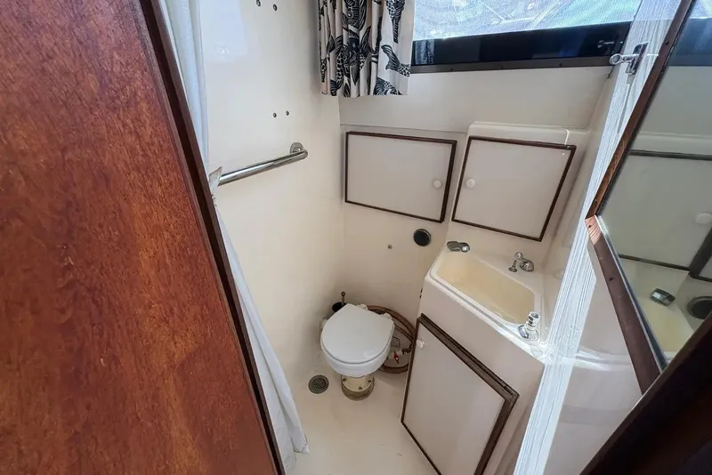 Slide: The Image of 1983 Hatteras Yachts 32 bathroom interior with sink, toilet, and storage cabinets. - 9