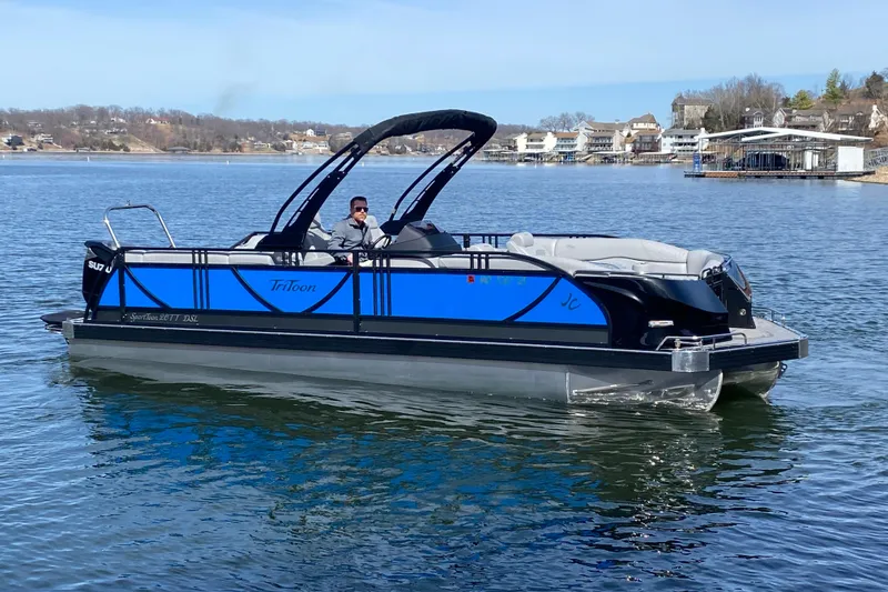 The Image of 2025 JC Sporttoon 26TT pontoon boat on a lake with scenic background. - 0