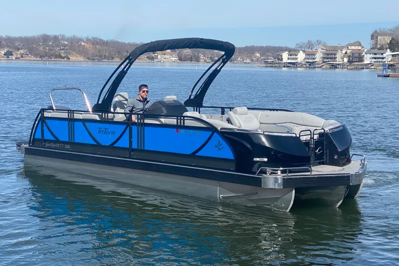 Slide: The Image of 2025 JC Sporttoon 26TT pontoon boat on a lake, featuring sleek design and blue accents. - 2