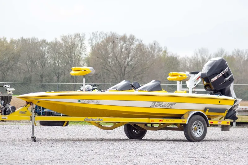 Slide: The Image of Yellow 2002 Bullet 20XDC boat with Mercury engine on trailer, parked outdoors. - 1