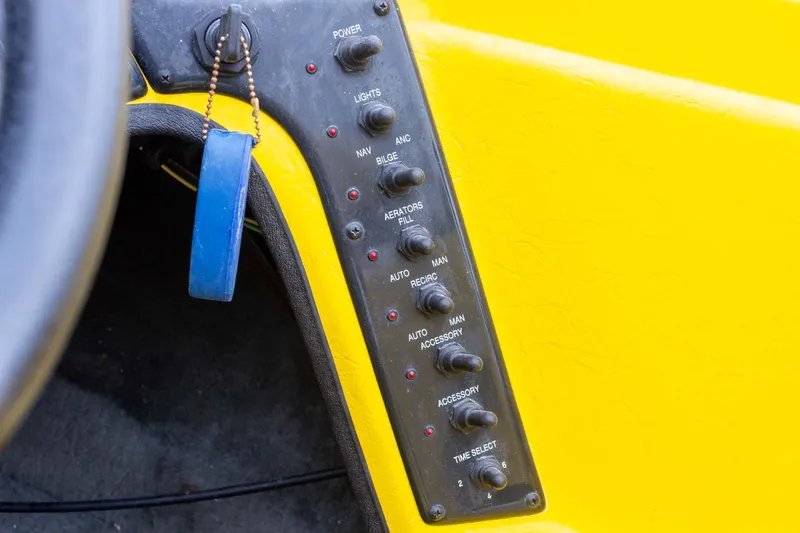 Slide: The Image of Control panel of a 2002 Bullet 20XDC boat with various switches and a blue keychain. - 24