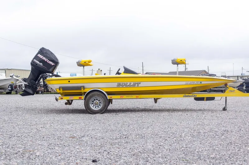Slide: The Image of Yellow 2002 Bullet 20XDC boat with Mercury outboard motor on gravel lot. - 6