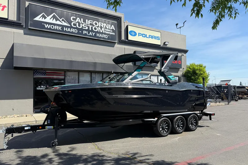 The Image of 2026 MasterCraft X24 boat on trailer outside California Custom dealership. - 0