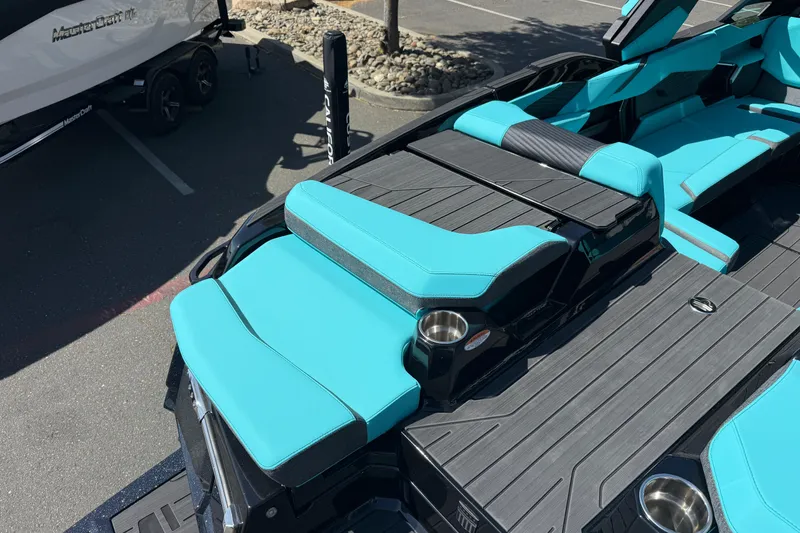 Slide: The Image of 2026 MasterCraft X24 boat with turquoise seating and sleek design in a parking lot. - 19
