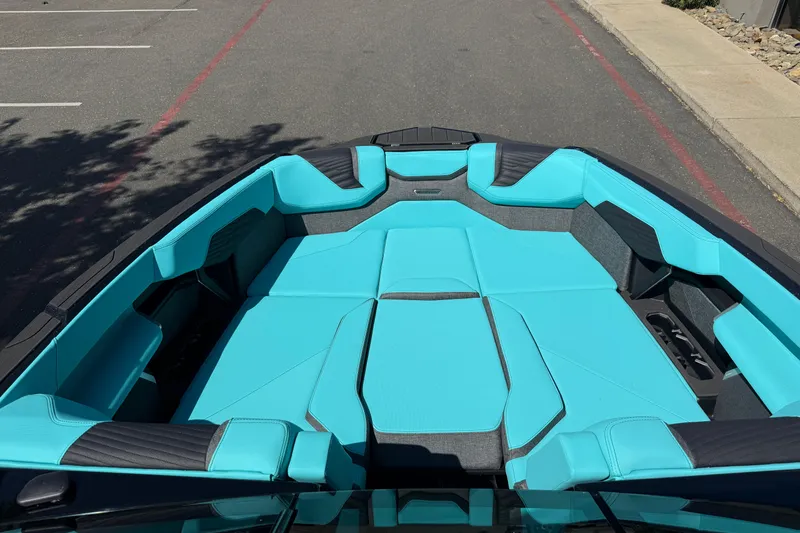 Slide: The Image of 2026 MasterCraft X24 boat interior with turquoise seating, parked on pavement. - 47