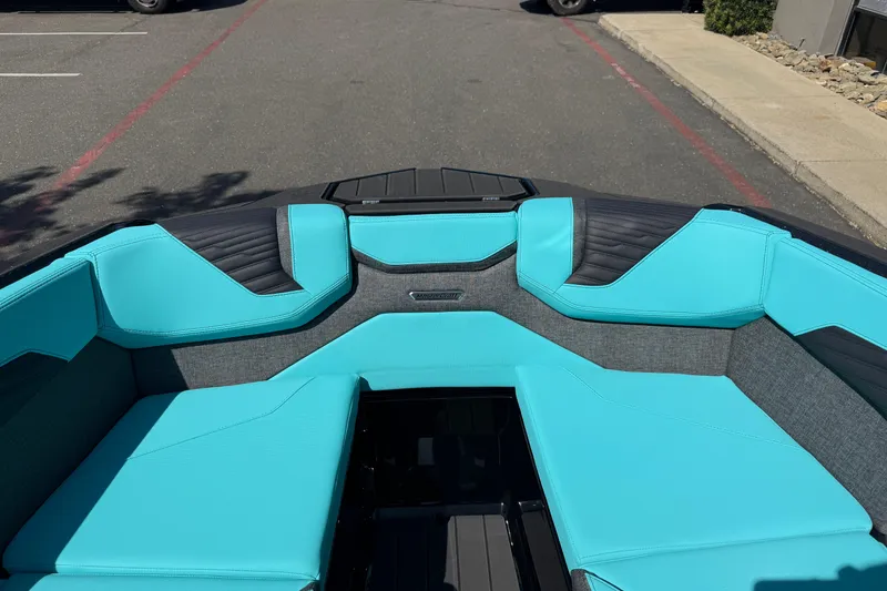 Slide: The Image of 2026 MasterCraft X24 boat interior with turquoise and black seating, parked on pavement. - 54