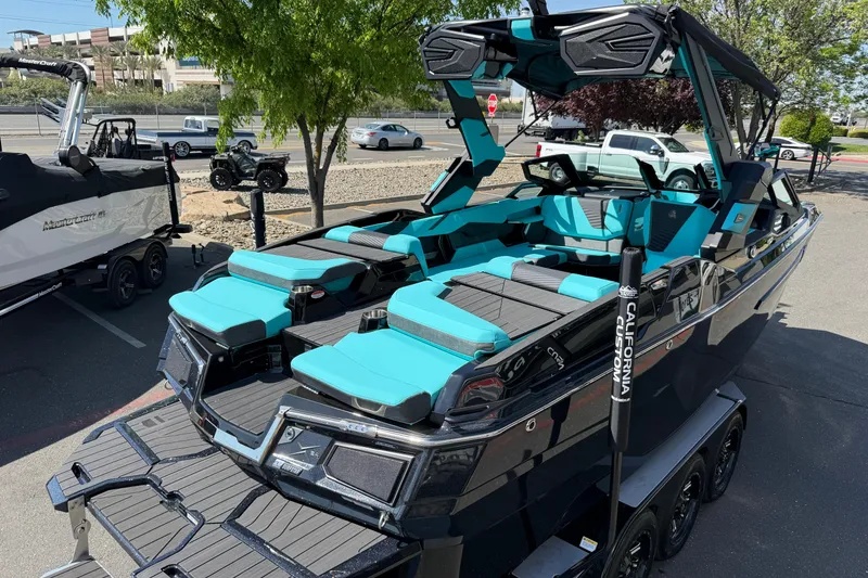 Slide: The Image of 2026 MasterCraft X24 boat with teal and black seating, parked on a trailer. - 65