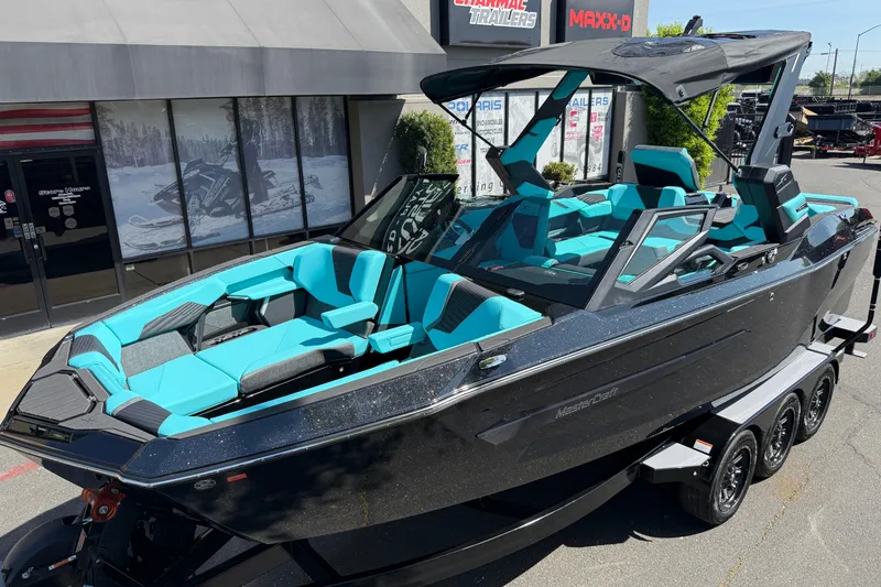 Slide: The Image of 2026 MasterCraft X24 boat with sleek design and vibrant turquoise seating, parked outside a dealership. - 67