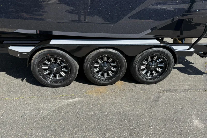 Slide: The Image of 2026 MasterCraft X24 trailer with triple black alloy wheels on pavement. - 9