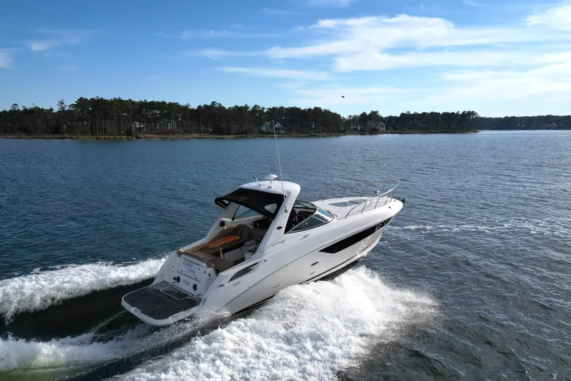 The Image of 2016 Sea Ray Sundancer 310 cruising on a serene lake under a clear blue sky. - 0