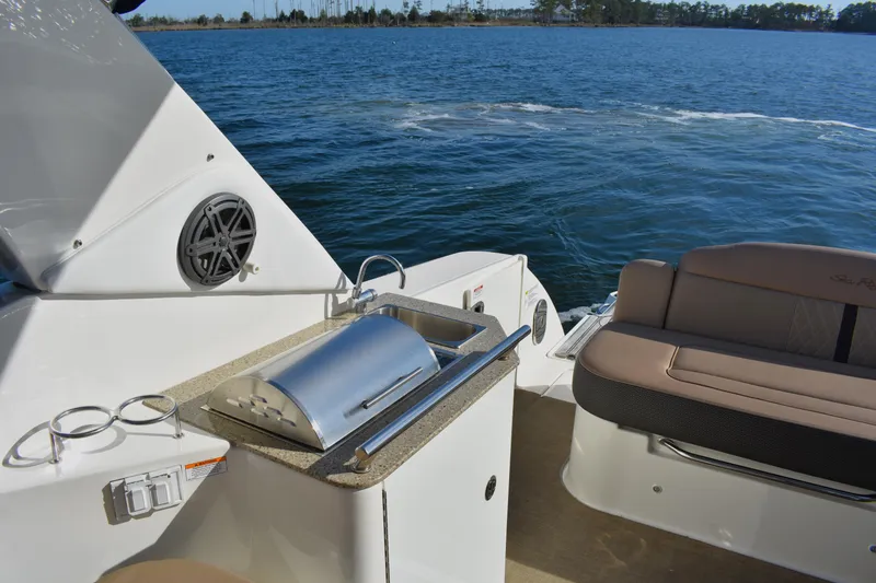 Slide: The Image of 2016 Sea Ray Sundancer 310 boat with outdoor grill and seating on calm water. - 12