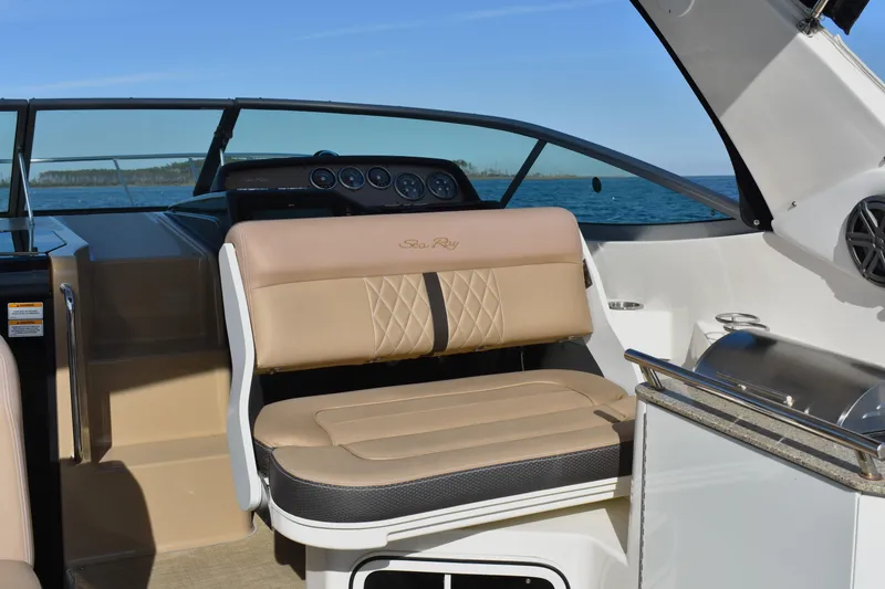 Slide: The Image of 2016 Sea Ray Sundancer 310 cockpit with beige seating and helm, overlooking the ocean. - 14