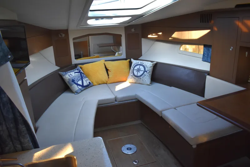 Slide: The Image of Interior of 2016 Sea Ray Sundancer 310 with cozy seating and nautical-themed pillows. - 30