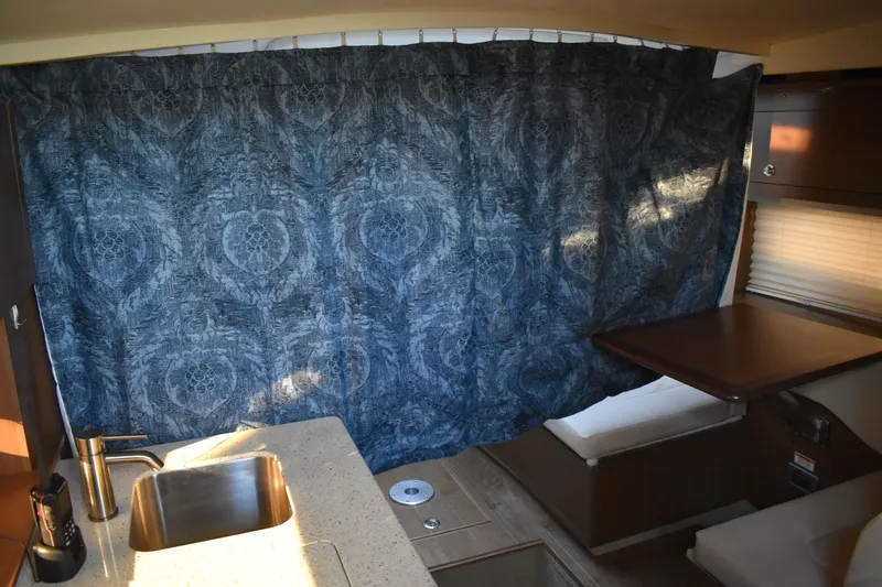 Slide: The Image of Interior of 2016 Sea Ray Sundancer 310 with blue curtain, sink, and seating area. - 31
