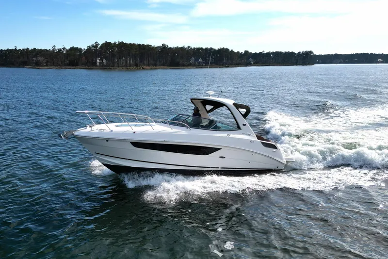 Slide: The Image of 2016 Sea Ray Sundancer 310 cruising on a serene lake with forested shoreline. - 8