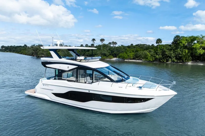 Slide: The Image of Luxury 2026 Cruisers Yachts 50 Fly on serene waterway, surrounded by lush greenery. - 17