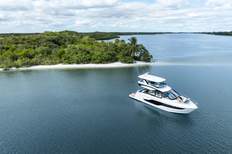 Slide: The Image of Luxurious 2026 Cruisers Yachts 50 Fly cruising near a lush, tropical island. - 21