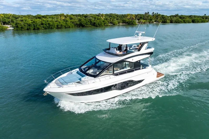 Slide: The Image of 2026 Cruisers Yachts 50 Fly cruising on a serene waterway, surrounded by lush greenery. - 24